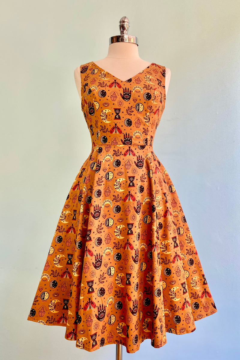  Composed of bronze fabric with a print in black, tan and sienna of crystals, moons, stars, mystical motifs and moths! This dress has a little give to the fabric which makes it very comfortable to wear.  There is a back zipper, hidden side pockets and is unlined.    Made in the USA
